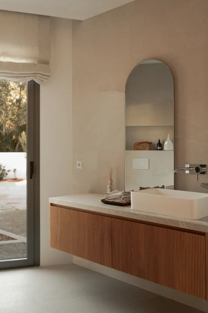 Lavabo con espejo en arco en el baño del proyecto Pinar de Sa Dutxeta